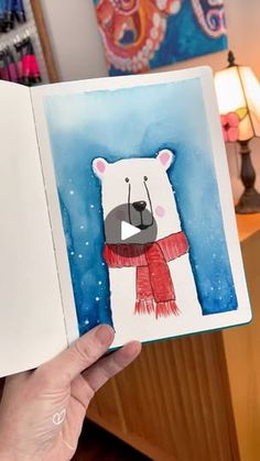 a person holding up an open book with a drawing of a polar bear on it