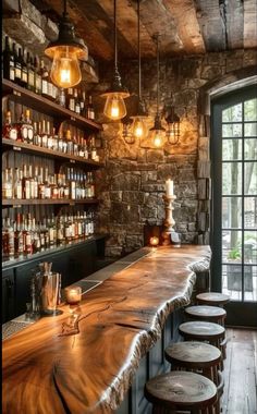 a long wooden bar with stools and lights hanging from it's ceiling in a stone walled room