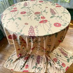 a round table covered with a flowered cloth on top of a hard wood floor