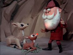 a santa clause is standing next to two deer in front of him and another reindeer on the ground