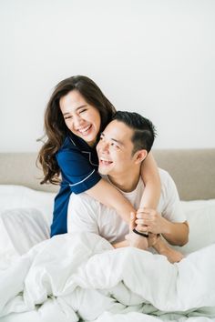 a man and woman laying on top of each other in bed smiling at each other