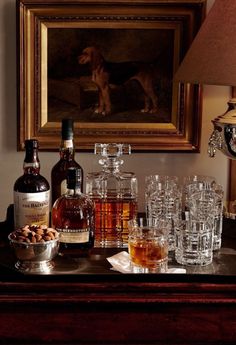 a table topped with bottles and glasses next to a painting