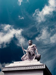 black and white photograph of a statue on top of a building with clouds in the background