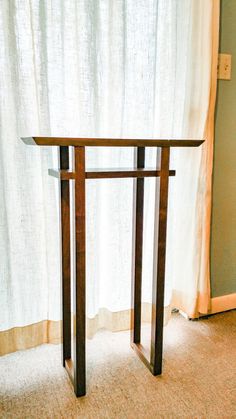 a wooden table sitting in front of a window next to a white drapes covered curtain