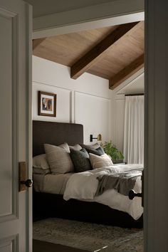 a large bed sitting under a wooden ceiling next to a doorway in a room with white walls