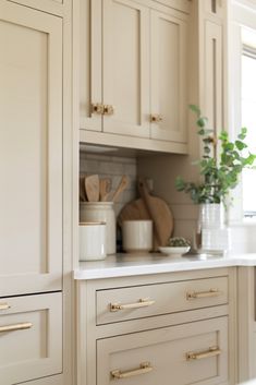 the kitchen cabinets are all white and have gold pulls on them, along with pots and pans