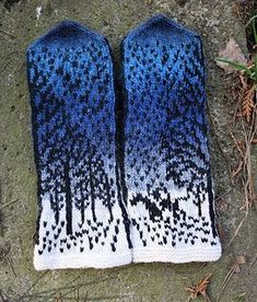 two blue and white mittens sitting on top of a cement ground next to grass