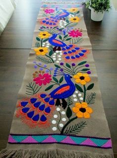 a long table runner with colorful flowers and birds on it, in the middle of a room