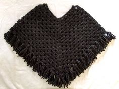 a black crocheted shawl laying on top of a white bed coverlet