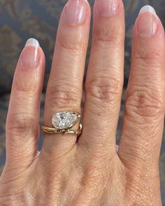 a close up of a person's hand with a diamond ring on her finger