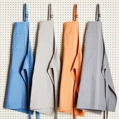 four different colored aprons hanging on a wall