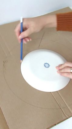 a person is holding a pencil near a paper plate