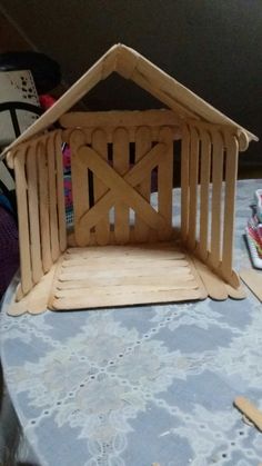 a wooden house sitting on top of a table next to scissors and other crafting supplies