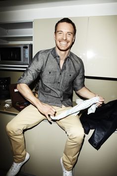 a man sitting on top of a kitchen counter holding a piece of paper in his hand