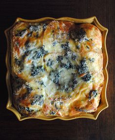 a casserole dish with cheese and spinach in it on a wooden table