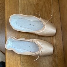 two pairs of ballet shoes sitting on top of a wooden floor