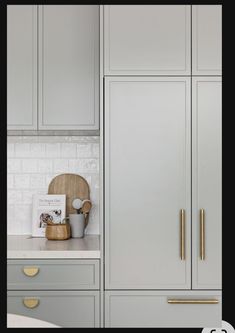 a kitchen with gray cabinets and gold handles on the doors, along with a white counter top