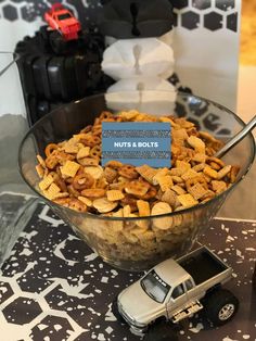 a glass bowl filled with cereal next to a toy truck on top of a table