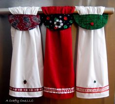 three christmas themed kitchen towels hanging on a towel rack