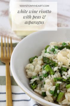 a white bowl filled with rice and asparagus next to a glass of wine