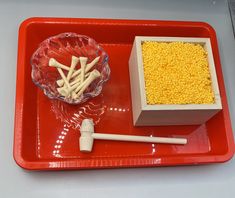 a red tray topped with a bowl of corn and marshmallows on top of it