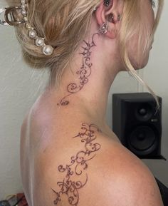 a woman with a tattoo on her neck and behind her ear is looking to the side