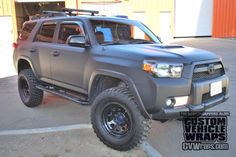 a gray toyota truck parked in front of a yellow garage door with the words custom vehicle wraps on it's side