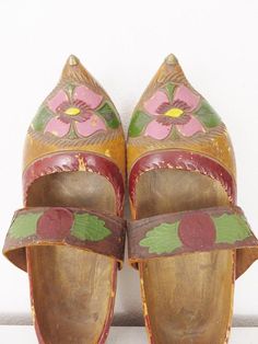 a pair of wooden shoes with painted flowers on them