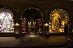 a store front with christmas decorations and lights on it's display windows at night