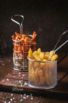 two metal baskets filled with food sitting on top of a wooden table next to each other