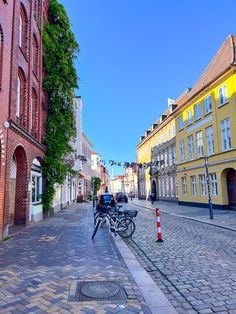 two bicycles parked on the side of a cobblestone street next to tall buildings