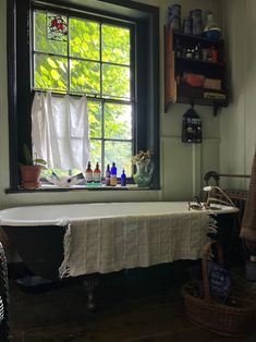 a bath tub sitting under a window next to a shelf with bottles on top of it