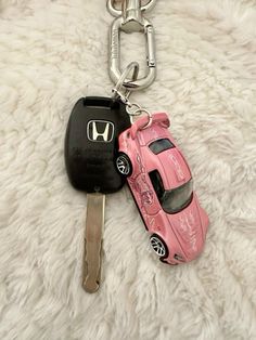 a pink car keychain with a black one on top and a red one on the bottom