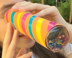 a girl looking through a paper tube with colorful beads on it and her eyes closed