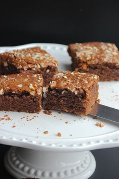 four pieces of brownie on a white plate with a knife