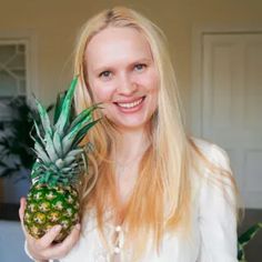 a woman holding a pineapple in her hand