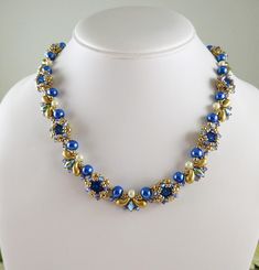 Woven Necklace Royal Blue with Shaped Beads and Crystals Gorgeous, hand woven necklace features Swarovski crystals in Royal blue paired with sparkling Tanzanite crystals and highlighted with blue and creamy white crystal pearls  that are woven with multiple two hole beads and  tiny golden seed beads.  A textured, colorful necklace. The approximate width of the necklace is just over .5"  and length 18". A spring ring clasp with a 2.5" extender chain completes this piece.  Necklace design by Isabella Lam. https://www.etsy.com/shop/IndulgedGirl Blue Pearl Jewelry With Spacer Beads, Luxury Sapphire Necklace With Polished Beads, Luxury Blue Victorian Necklaces, Elegant Royal Blue Gemstone Necklace, Luxury Antique Blue Necklace, Elegant Sapphire Beaded Necklace, Adjustable, Woven Necklace, White Crystal, Colourful Necklace