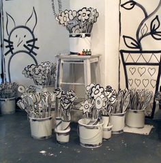 several buckets with flowers painted on them are sitting in front of a wall mural