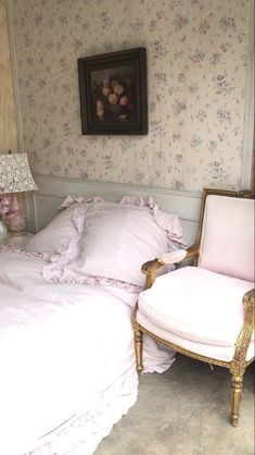 a chair and bed in a room with floral wallpaper