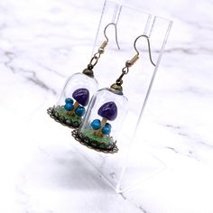 the earrings are made from glass and have mushrooms in them with blue beads on them