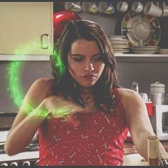 a woman standing in a kitchen with green light coming from her hands and looking at the camera