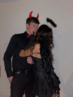 a man and woman are dressed up as devilish couples in black outfits, standing next to each other