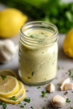 a mason jar filled with lemon, garlic and parsley next to sliced lemons