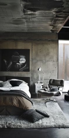 a bedroom with concrete walls and flooring is shown in black and white colors, including the bed