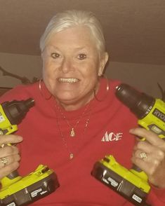 an older woman holding two electric drillers in her hands