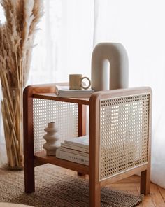 a coffee table with some items on it and a vase next to it in front of a window