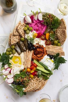 a platter filled with different types of food on top of a table next to wine glasses