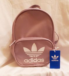 This lavender Adidas Originals Santiago Mini Backpack is a must-have for women who love to travel or need a stylish and lightweight bag for everyday use. The exterior is made of durable polyester in soft vision purple and white colors. The bag has a zip closure and adjustable strap with accents in strap, zipper, and logo design in purple hardware. The bag features inner pockets and pockets on the exterior, perfect for organizing your essentials. It has a solid pattern and is adorned with the Adidas logo. The lining is made of comfortable polyester in purple color, and the handle/strap is made of polyester material. This backpack is ideal for travel, school, or sports activities. Travel Sports, Adidas Originals Women, Lightweight Bag, Travel School, White Colors, Purple And White, Sports Activities, Sport Bag, Mini Backpack