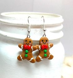 gingerbread man and woman earrings with green bead on ear wires in front of white jar