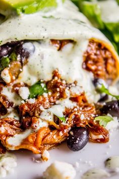 an enchilada with black olives, cheese and lettuce on it